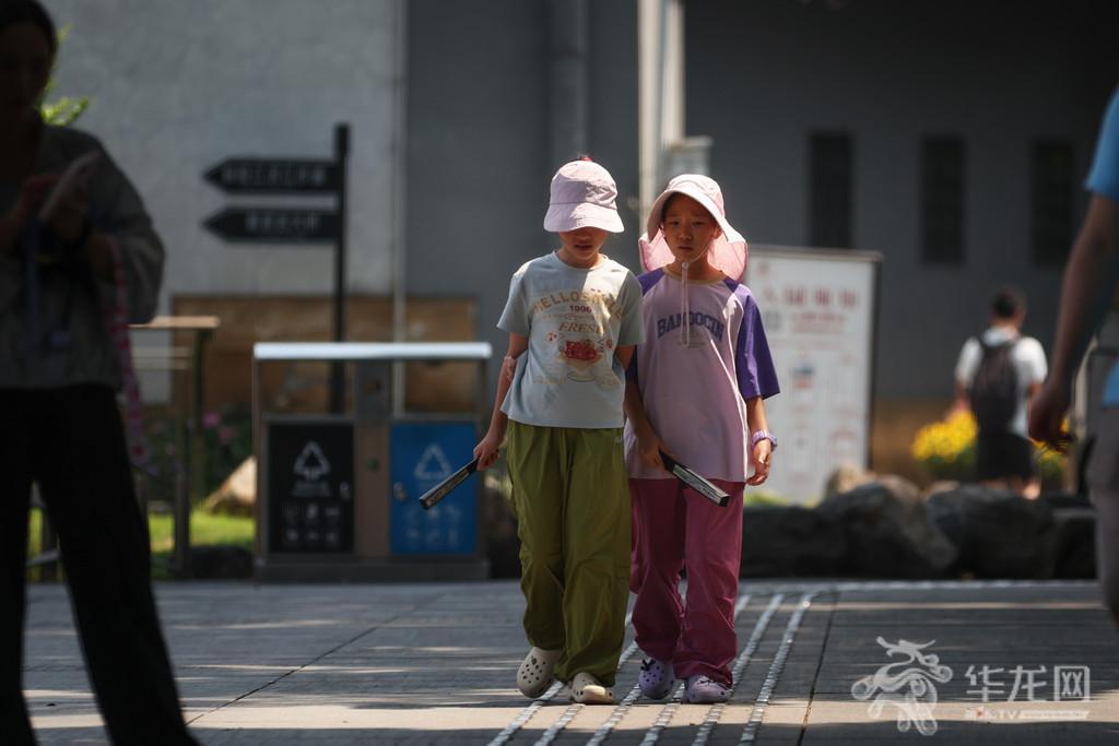 渝中区街头,两名孩童手持折扇,从容应对高温天气。第1眼TV-华龙网记者 李一鸣 摄