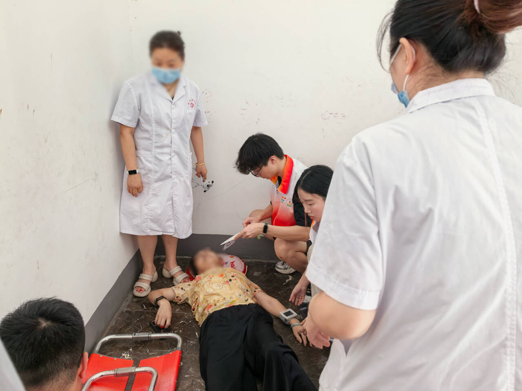 志愿者协助摔倒老人保持去枕平卧位并开展现场照护。受访单位供图
