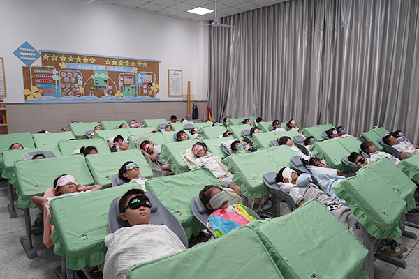 重庆市两江新区空港新城人和街小学学生在班主任的指导和帮助下使用可折叠课桌椅午睡。学校供图